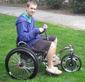 project student testing an electric motor hybrid drive for a 3-wheeled lever-drive wheelchair